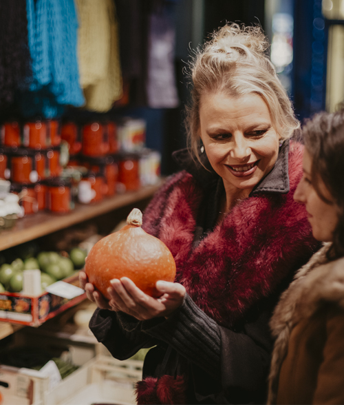 Celia Brooks in Borough Market holding an orange pumpkin.